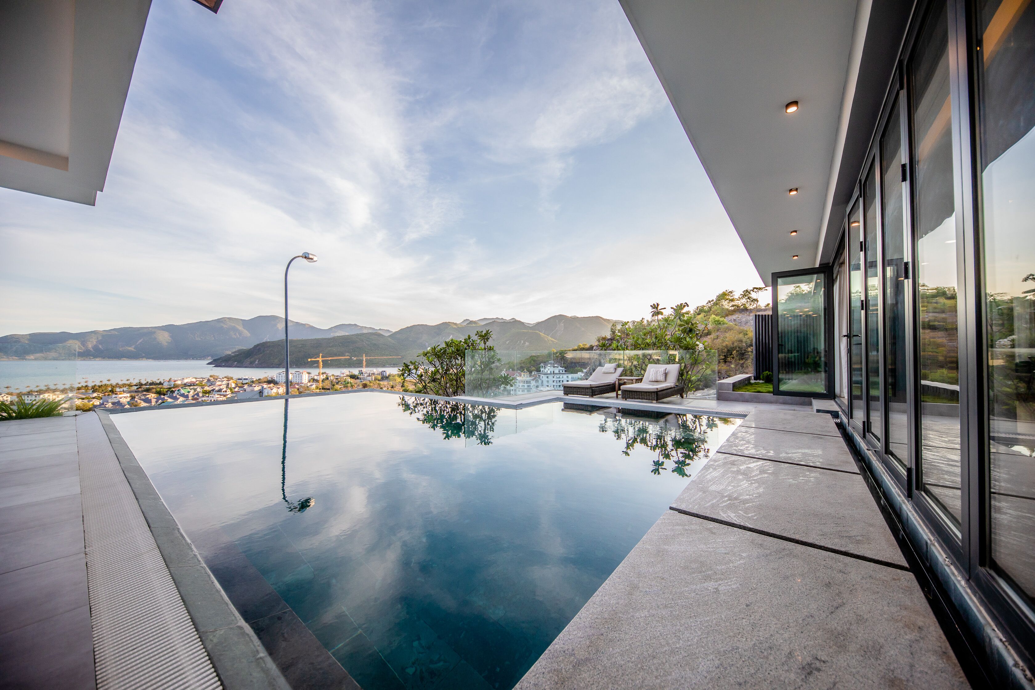 A modern infinity pool with a clear view of the ocean and mountains.