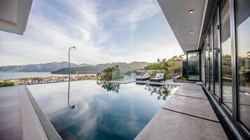 A modern infinity pool with a clear view of the ocean and mountains.