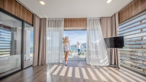 Et moderne hotelværelse med stor balkon, trægulv og fladskærms-tv.