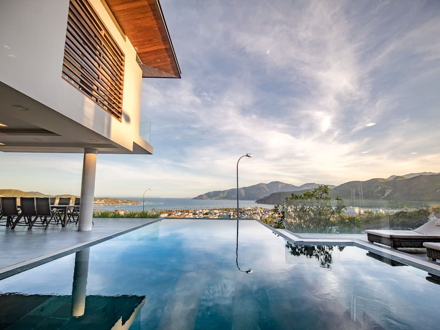 A modern infinity pool with a clear view of the sea and mountains.