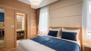 A modern hotel room with a large bed, wooden wardrobe, and a chandelier.