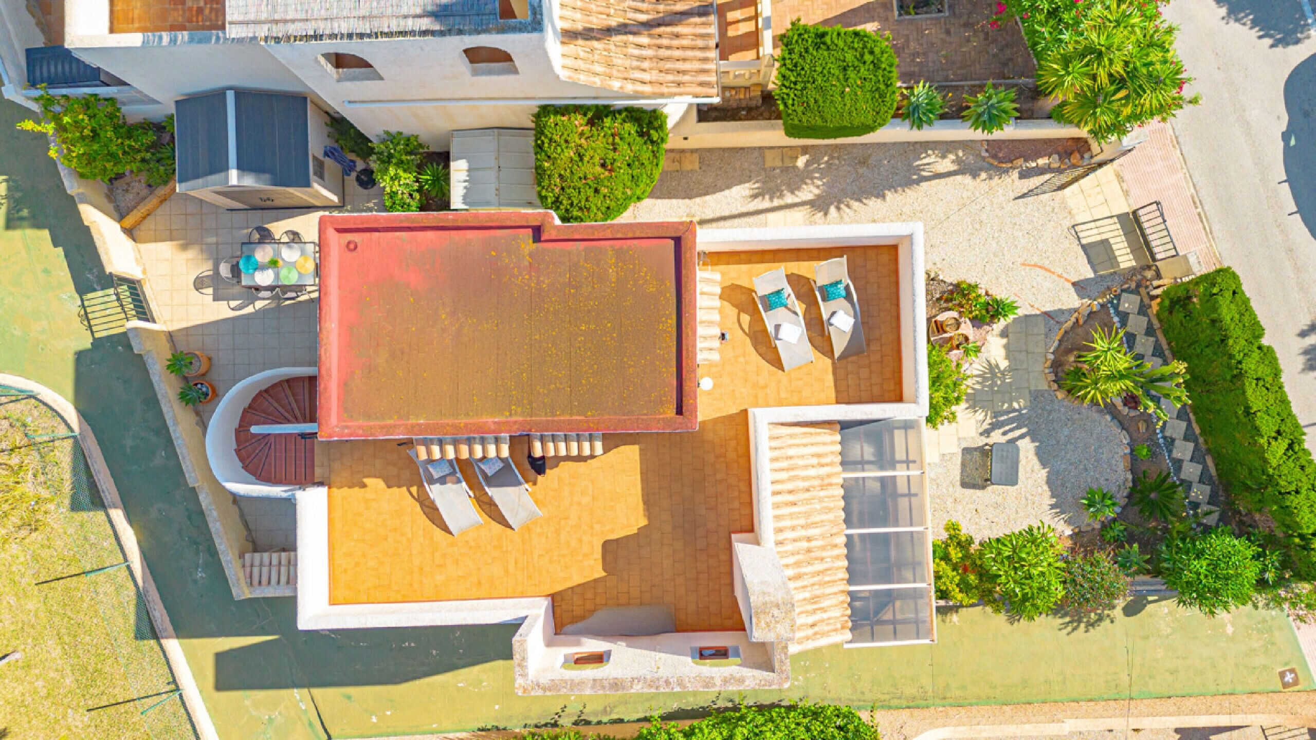 An aerial view of a modern house with a spacious patio, a swimming pool, and a well-maintained garden.