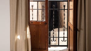 A room with a wooden door leading to an outdoor area with a metal gate.