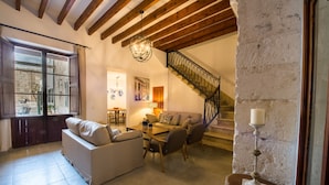 A cozy living room with a sofa, chairs, a coffee table, and a staircase.