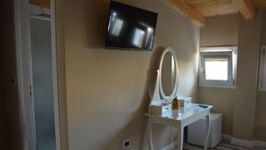A bedroom with a TV mounted on the wall, a bedside table with a mirror, a small dresser, and a window with a view of the outside. - B&B Domus Palmi (Palmi)