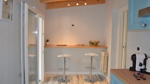 A kitchen with two bar stools, a wooden countertop, and a coffee machine. - B&B Domus Palmi (Palmi)