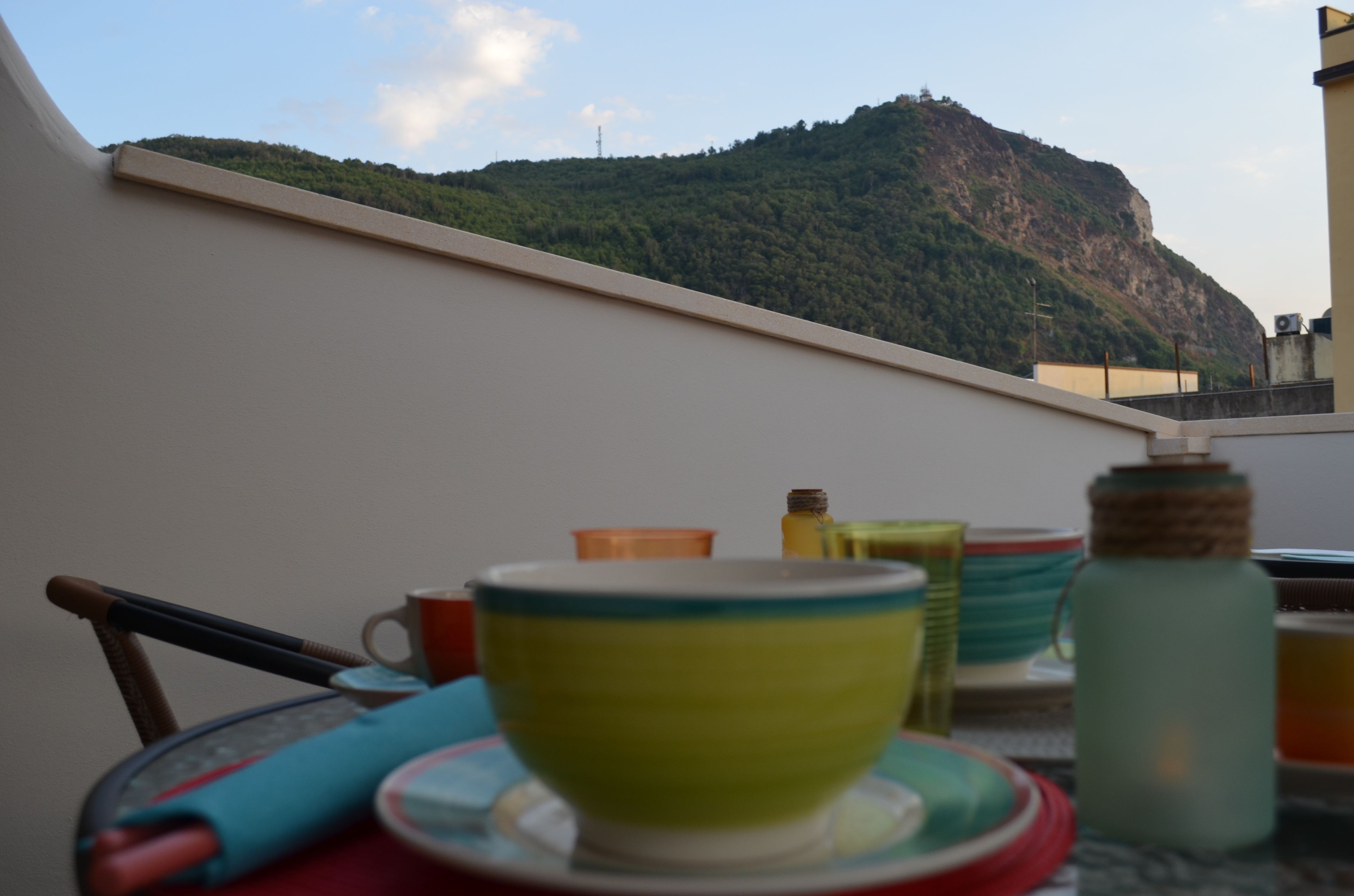 Une table à manger avec de la vaisselle aux couleurs vives et une vue sur une montagne.