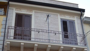 A two-story building with a balcony, large wooden doors, and a garage. - B&B Domus Palmi (Palmi)
