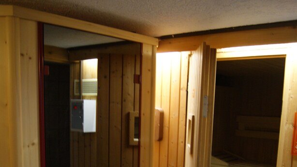 A wooden interior with a visible door leading to another room, a small window, and a radiator. - Gästehaus Charlotte (Bayrischzell)