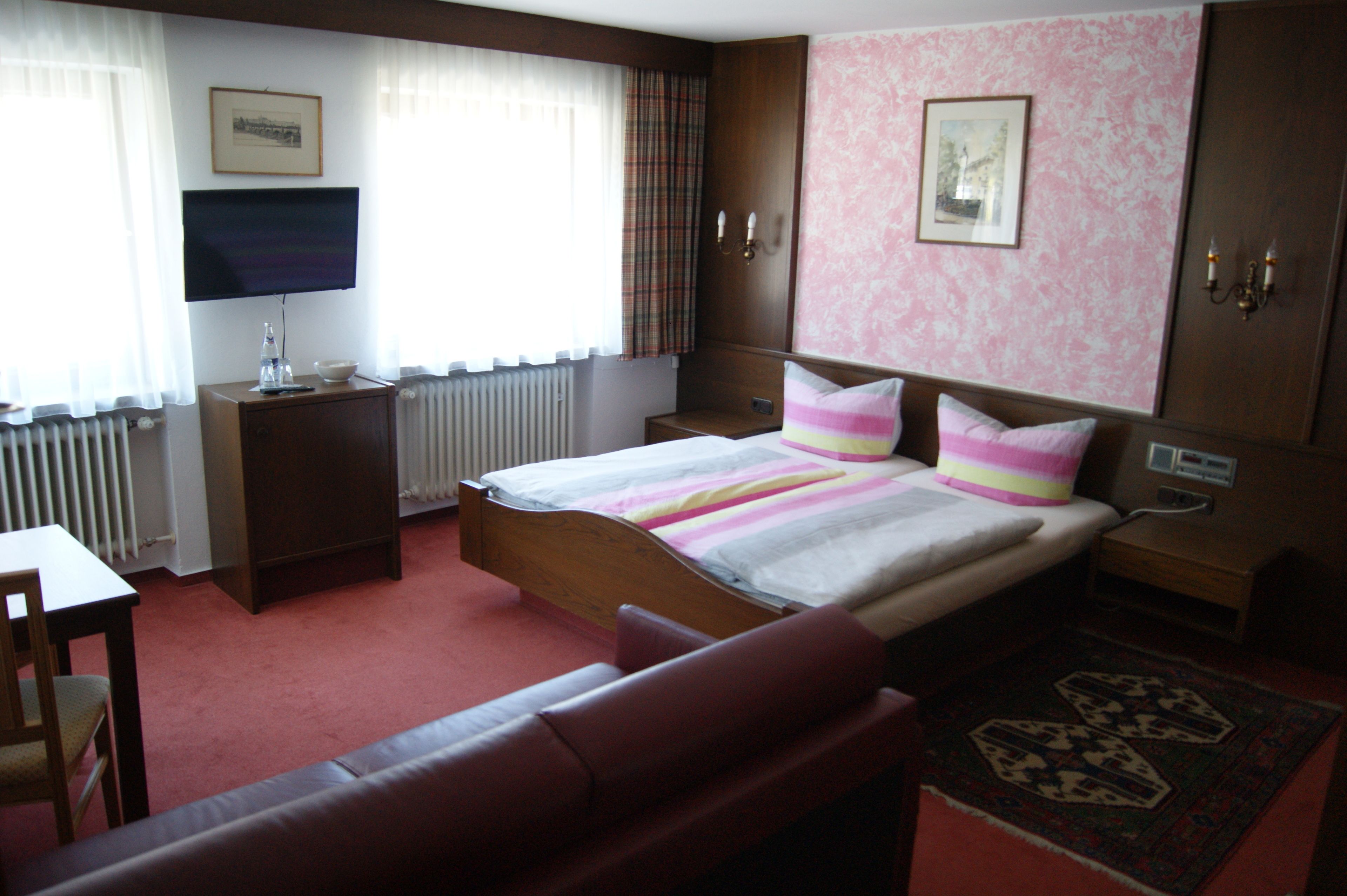 Una habitación de hotel con cama, televisor, escritorio y sofá.