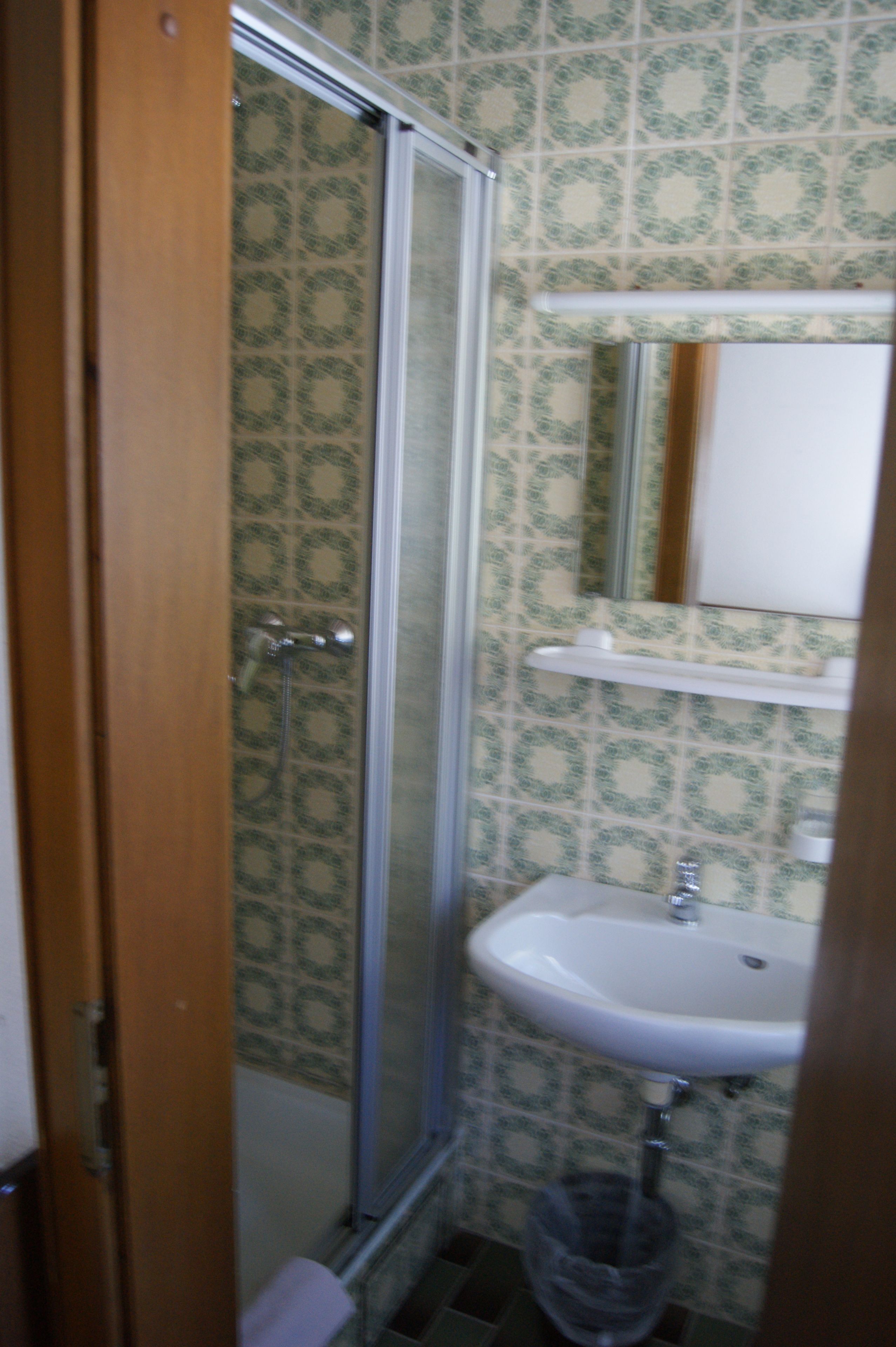 Une salle de bain avec une douche, un lavabo et des carreaux décorés.
