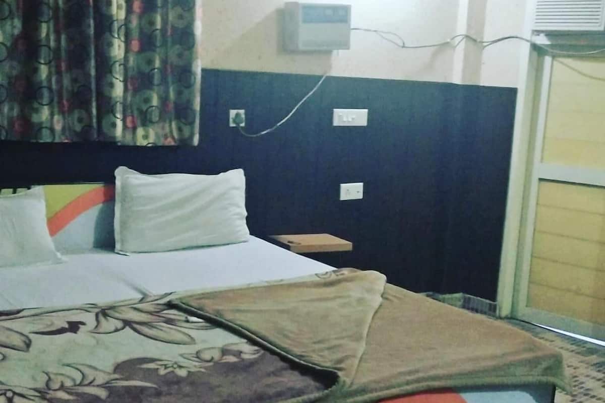 A bed with a floral bedspread, a headboard, and a wall-mounted air conditioning unit.