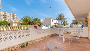 A balcony with two lounge chairs, a table, and a decorative fence. - Apartament Arenal 1 - PlusHolidays (Calpe)