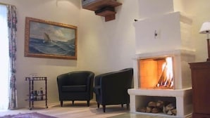 A living room with a fireplace, two armchairs, a painting, and a television mounted on the wall. - Best Bed (Herning)