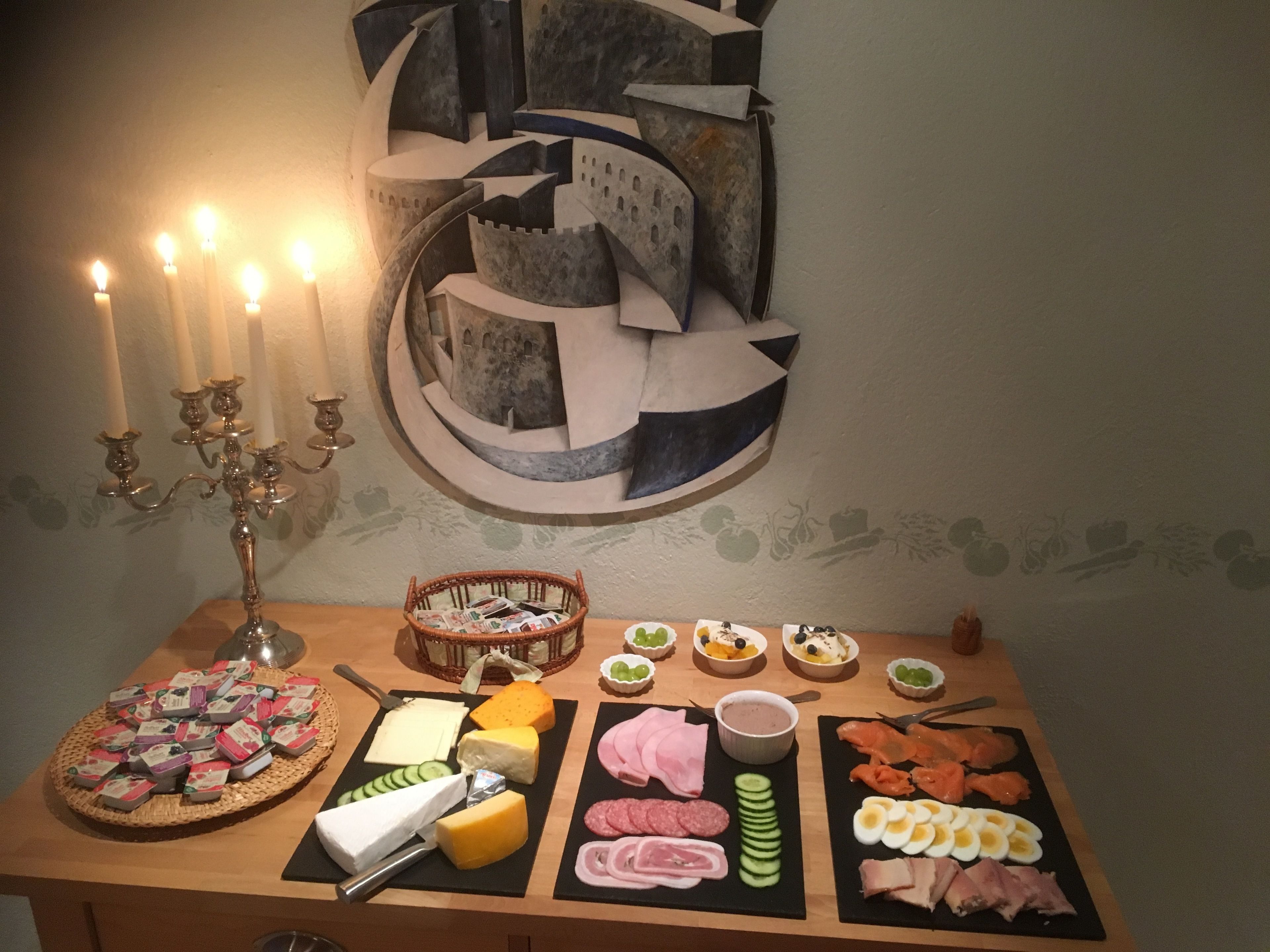 A table with various food items, including cheeses, meats, and fruits, arranged on black placemats.