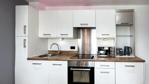 Una cocina moderna con armarios blancos, una campana extractora de acero inoxidable, un horno empotrado y una encimera de madera.