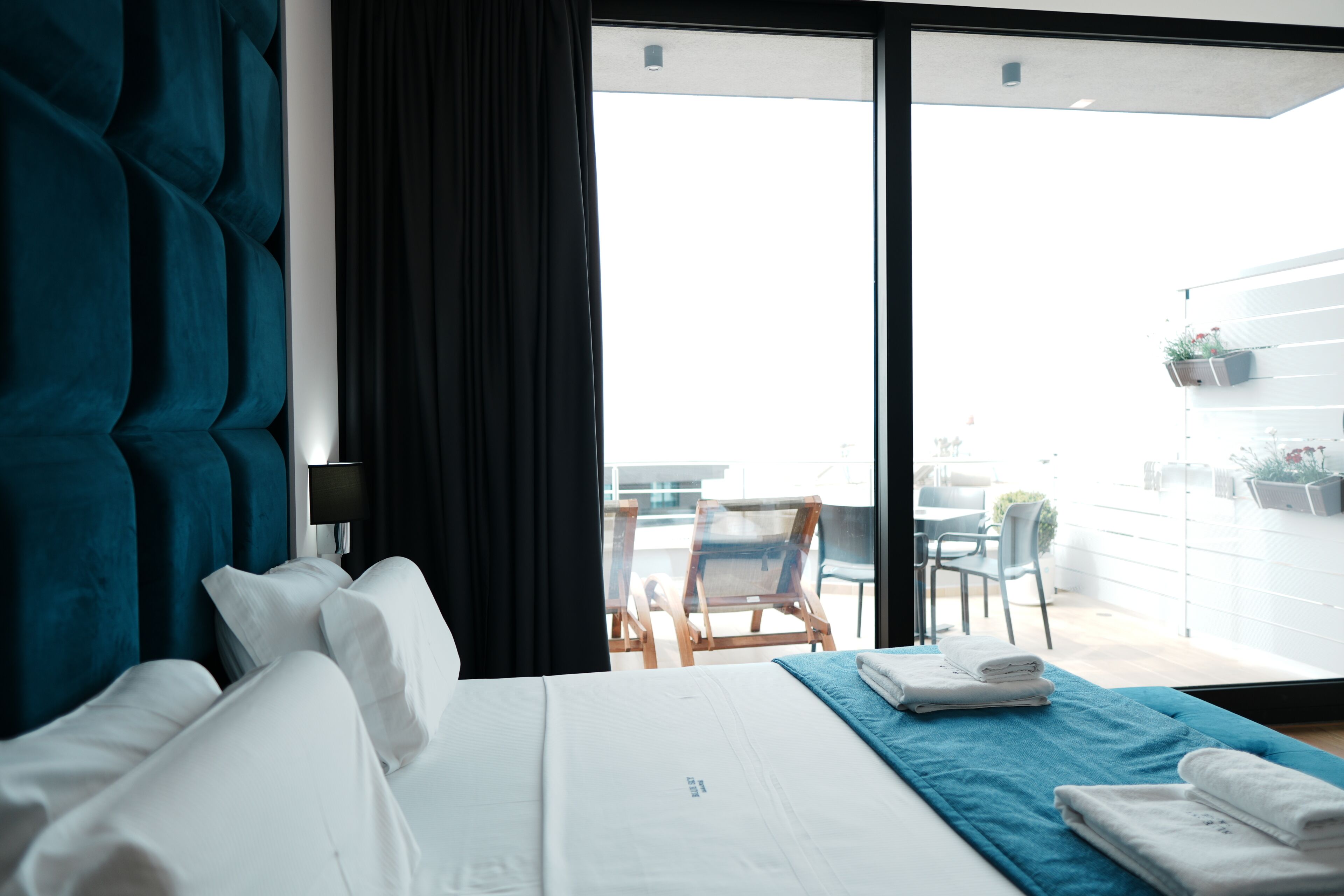 A hotel room with a bed, a blue towel, and a view of the outdoor area.