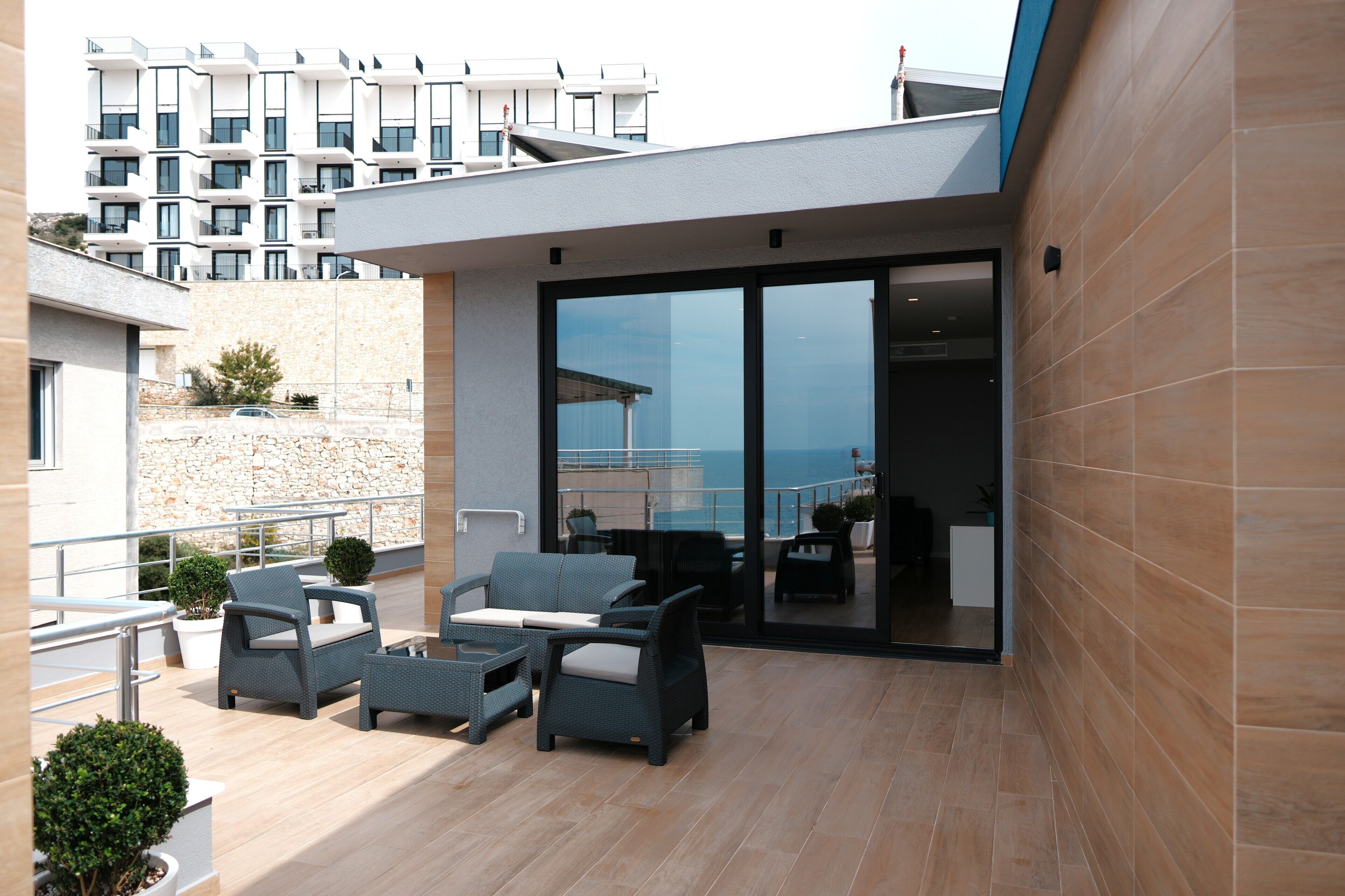 Un patio moderno al aire libre con mobiliario de mimbre, un muro de piedra y vistas a un edificio de gran altura.