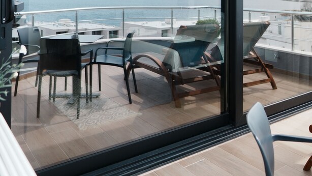Un balcon moderne avec vue sur la mer, aménagé avec des chaises et une table.