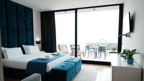 A modern hotel room with a large bed, a desk, a TV, and a balcony with a view. - Hotel Blue Sky (Sarandë)