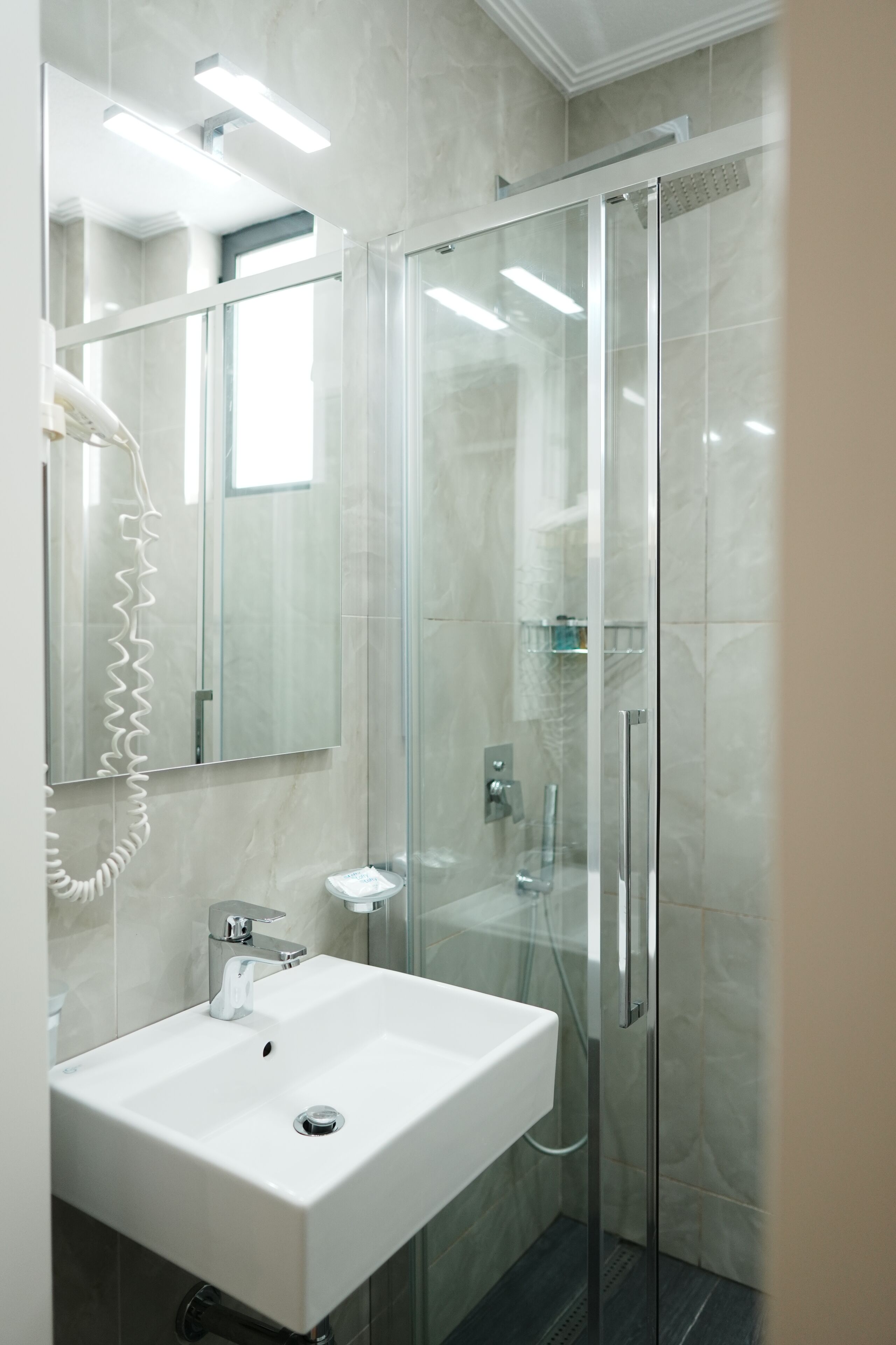 Une salle de bain moderne avec une douche à parois de verre, un lavabo blanc et un miroir.