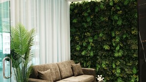 Un salon moderne avec un canapé, une table basse ronde, une plante en pot et un mur végétal.