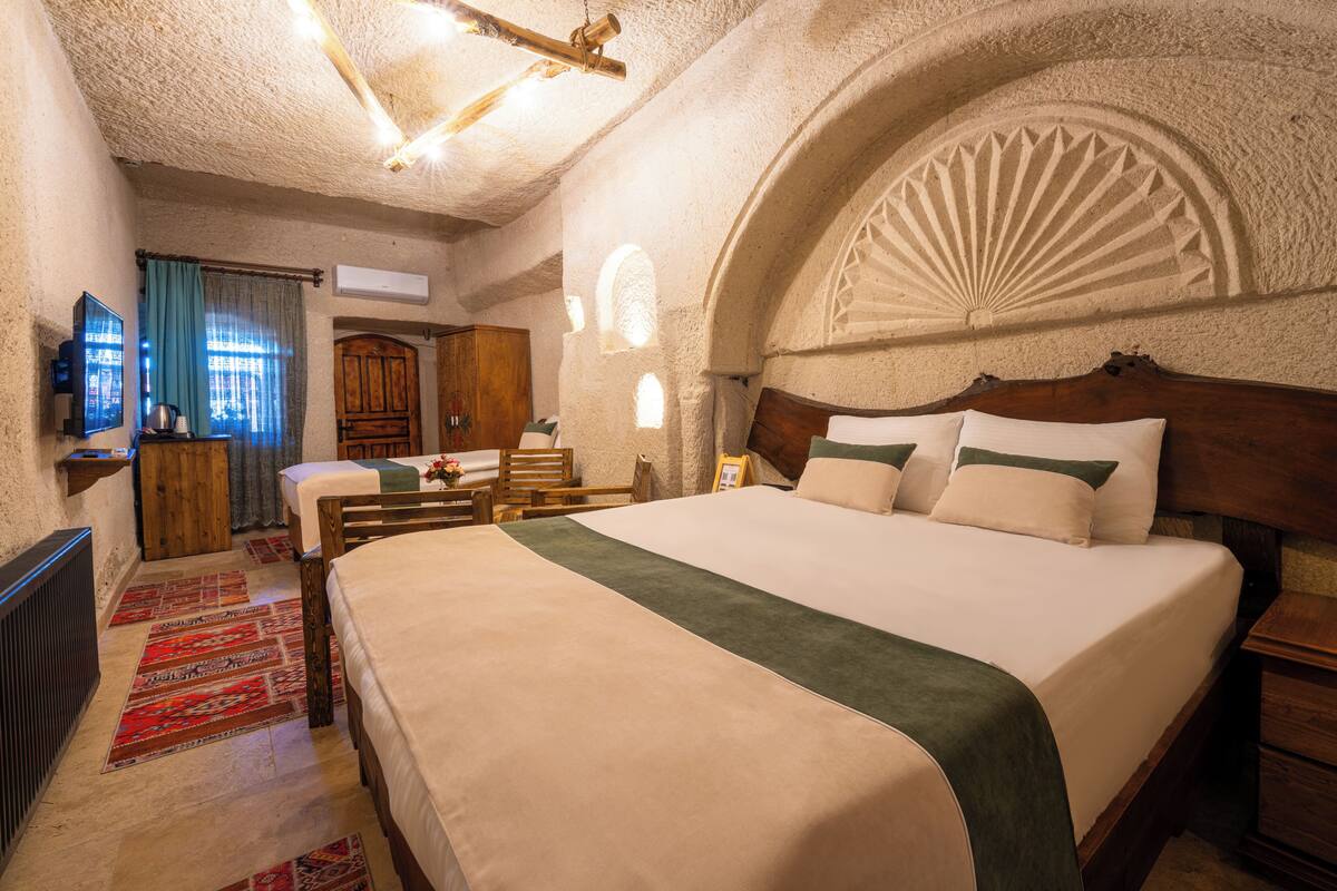 A spacious bedroom with a large bed, wooden headboard, and a decorative arched ceiling.