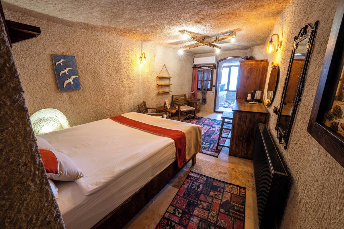 A cozy room with a large bed, a wooden desk, and a mirror.