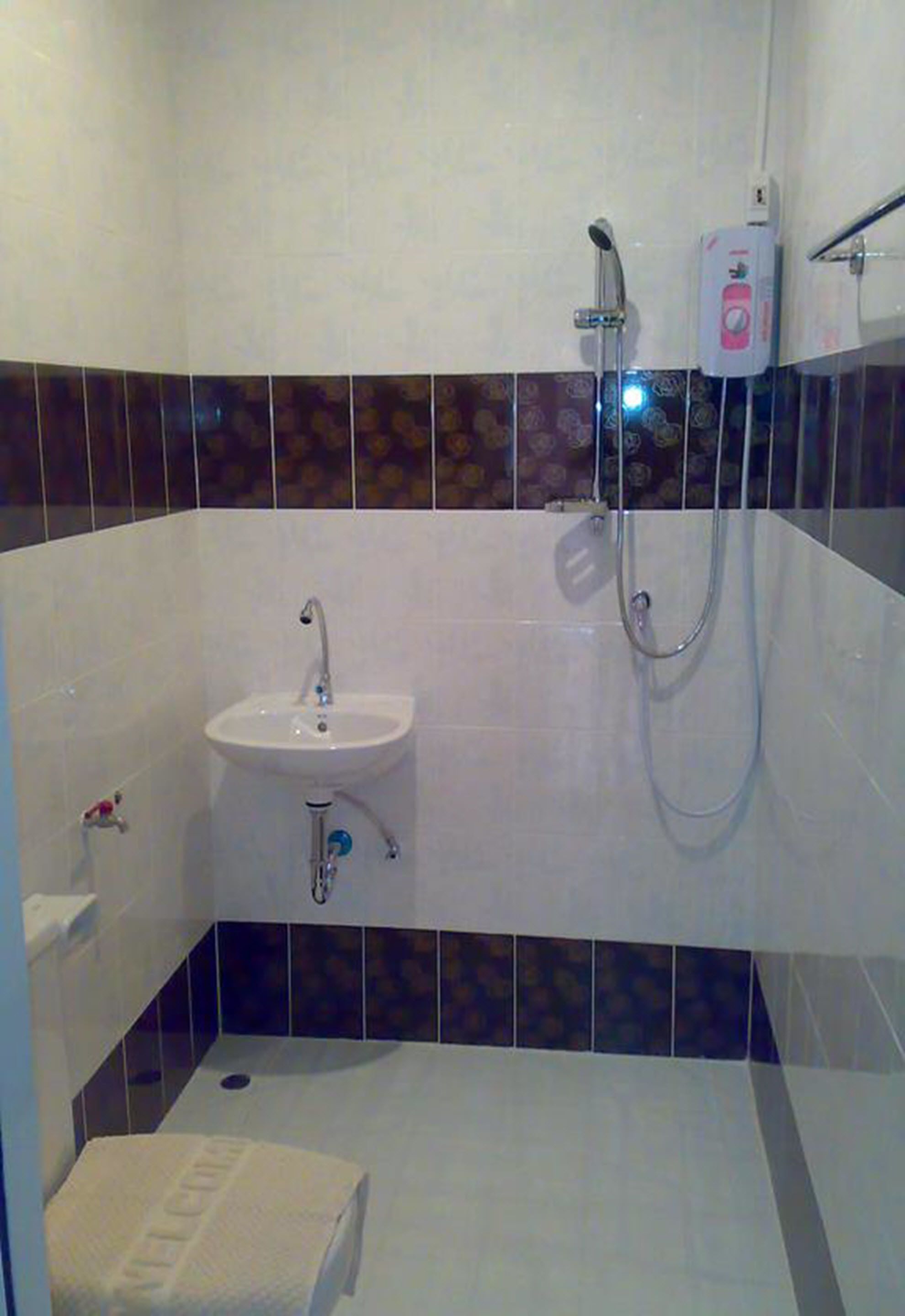 A bathroom with a sink, shower, and a towel rack.