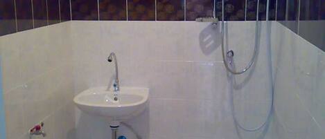 A bathroom with a sink, shower, and a towel rack.