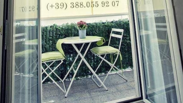 A restaurant with a glass door, a sign advertising breakfast, and a small table with chairs outside. - Best Season (Reggio Calabria)