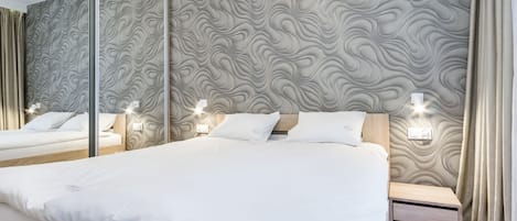 Une chambre moderne avec un grand lit, une table de chevet, un miroir et un mur orné d’un motif ondulé.