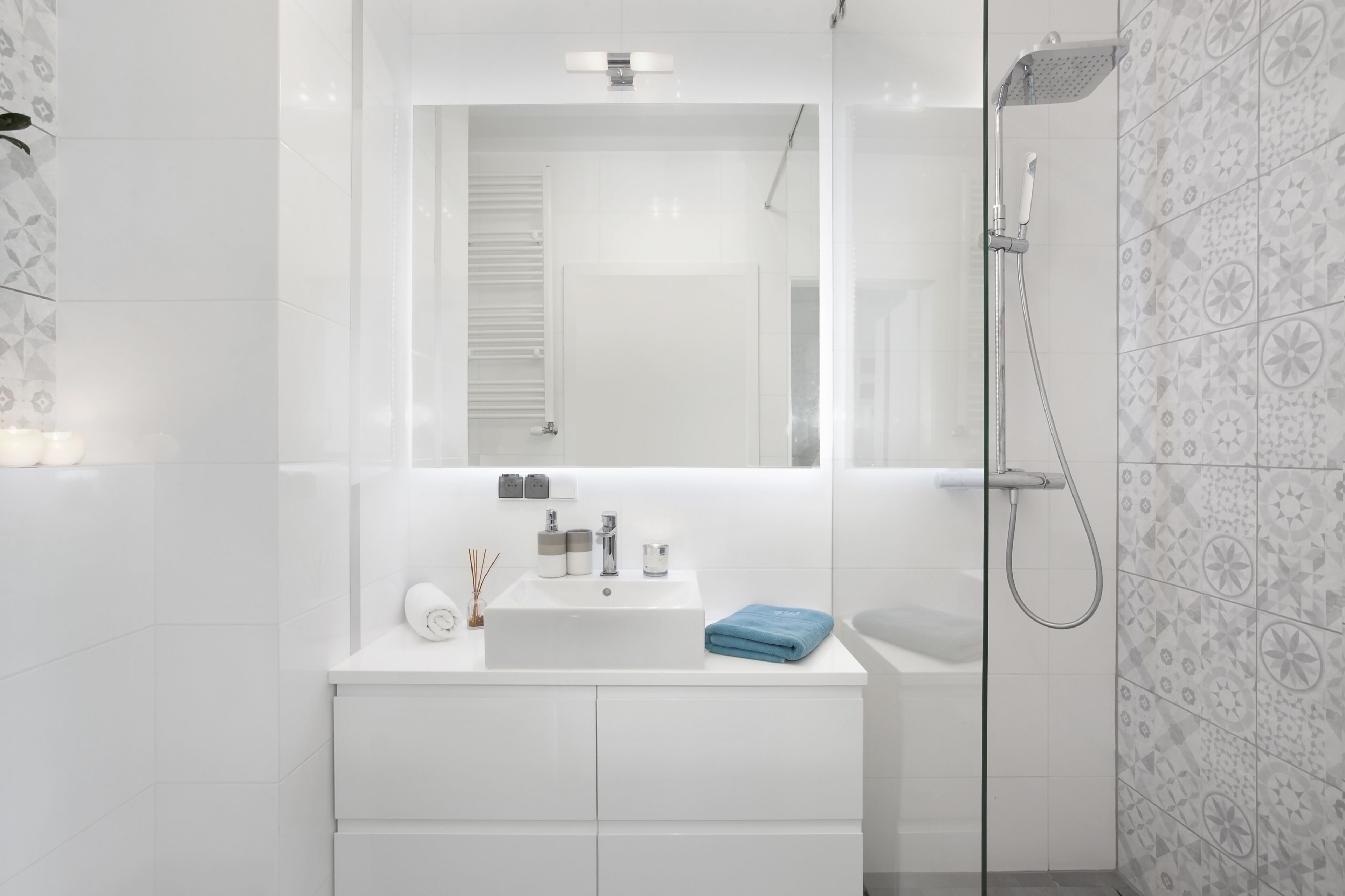 A modern bathroom with a white sink, mirror, and shower.
