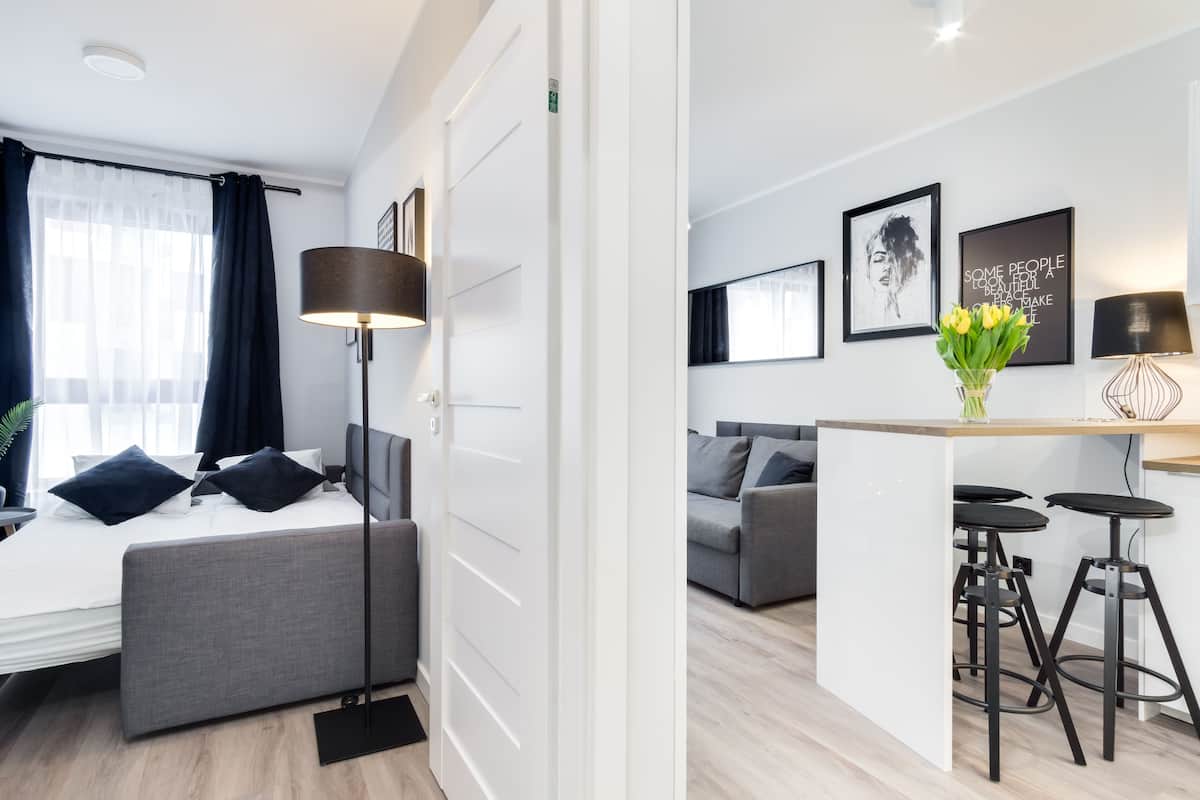 Una habitación de hotel moderna con cama, mesita de noche y zona de escritorio con taburetes.