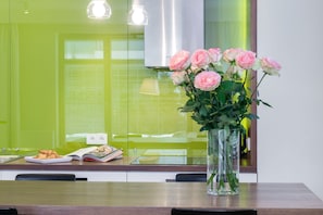 A kitchen counter with a vase of pink roses, a plate of croissants, and a magazine. - Elite Apartments Marina Residence (Gdansk)