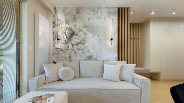 Una sala de estar moderna con un sofá color beige, un gran mural floral y un panel de pared de listones de madera.
