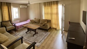 A living room with a sofa, armchairs, a coffee table, and a TV stand. - Menekse Apart (Trabzon)