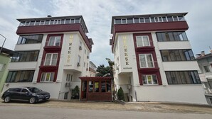 A building with two identical sections, each with a balcony and a sign reading 'MENEKSE REZIDANS'. - Menekse Apart (Trabzon)
