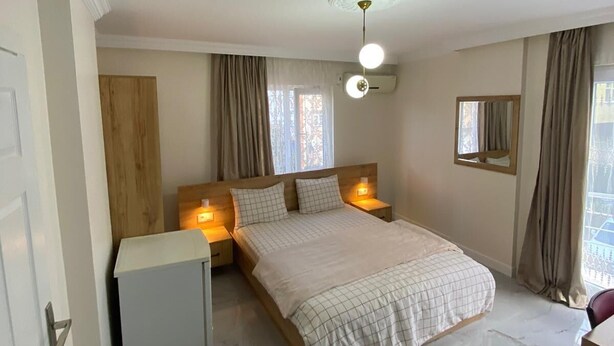 A bedroom with a bed, bedside tables, a ceiling fan, and a window with curtains. - Menekse Apart (Trabzon)
