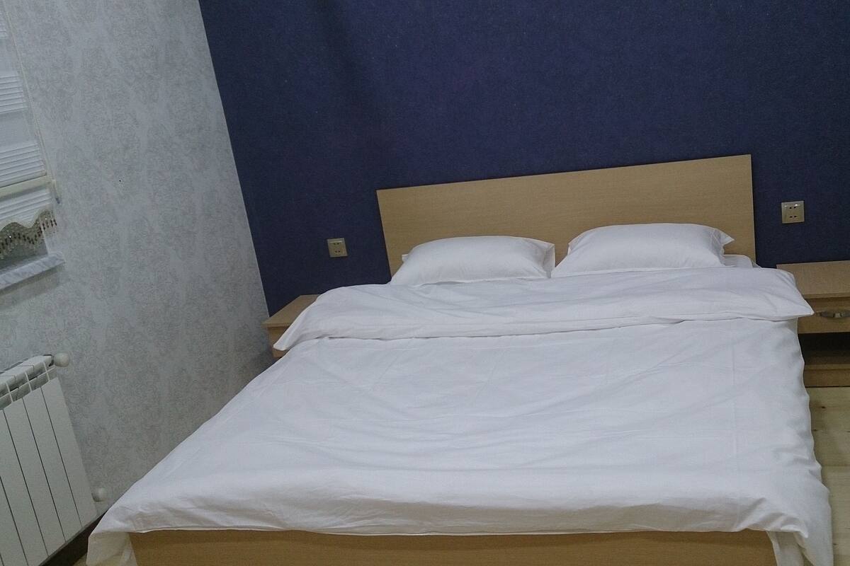 A single bed with white bedding in a room with blue walls and a wooden headboard.