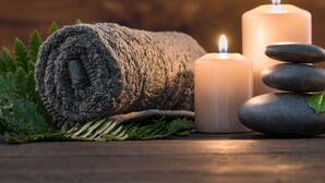 A rolled towel, two candles, and a stack of stones on a wooden surface. - Sara's Bed and Breakfast (Erikslund)