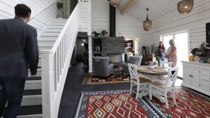 A spacious living area with a fireplace, a staircase, and a dining area with a patterned rug. - Sara's Bed and Breakfast (Erikslund)