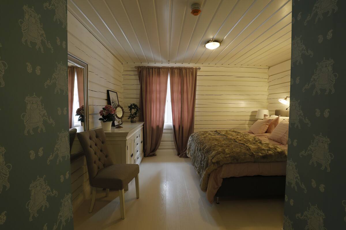 A bedroom with a bed, a chair, a dresser, and a window with curtains.