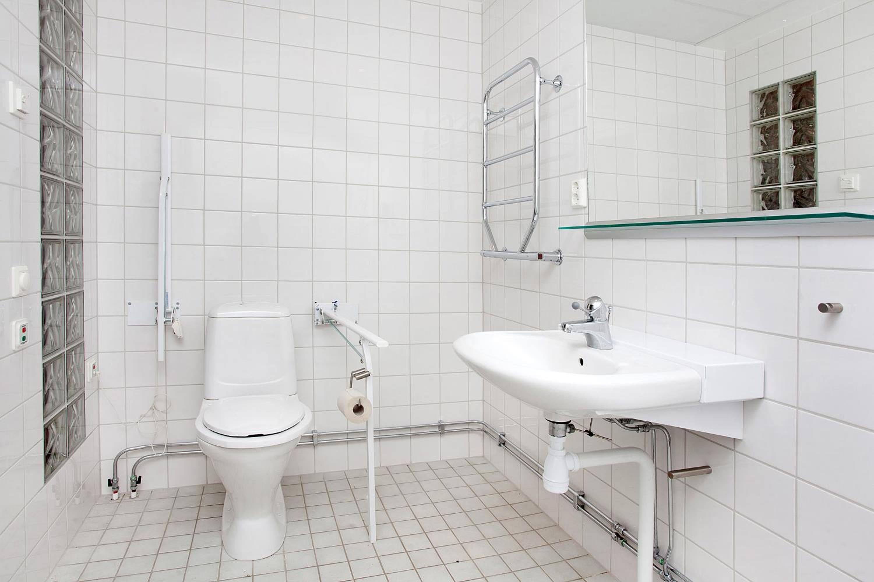 A bathroom with a toilet, sink, and glass shower enclosure.
