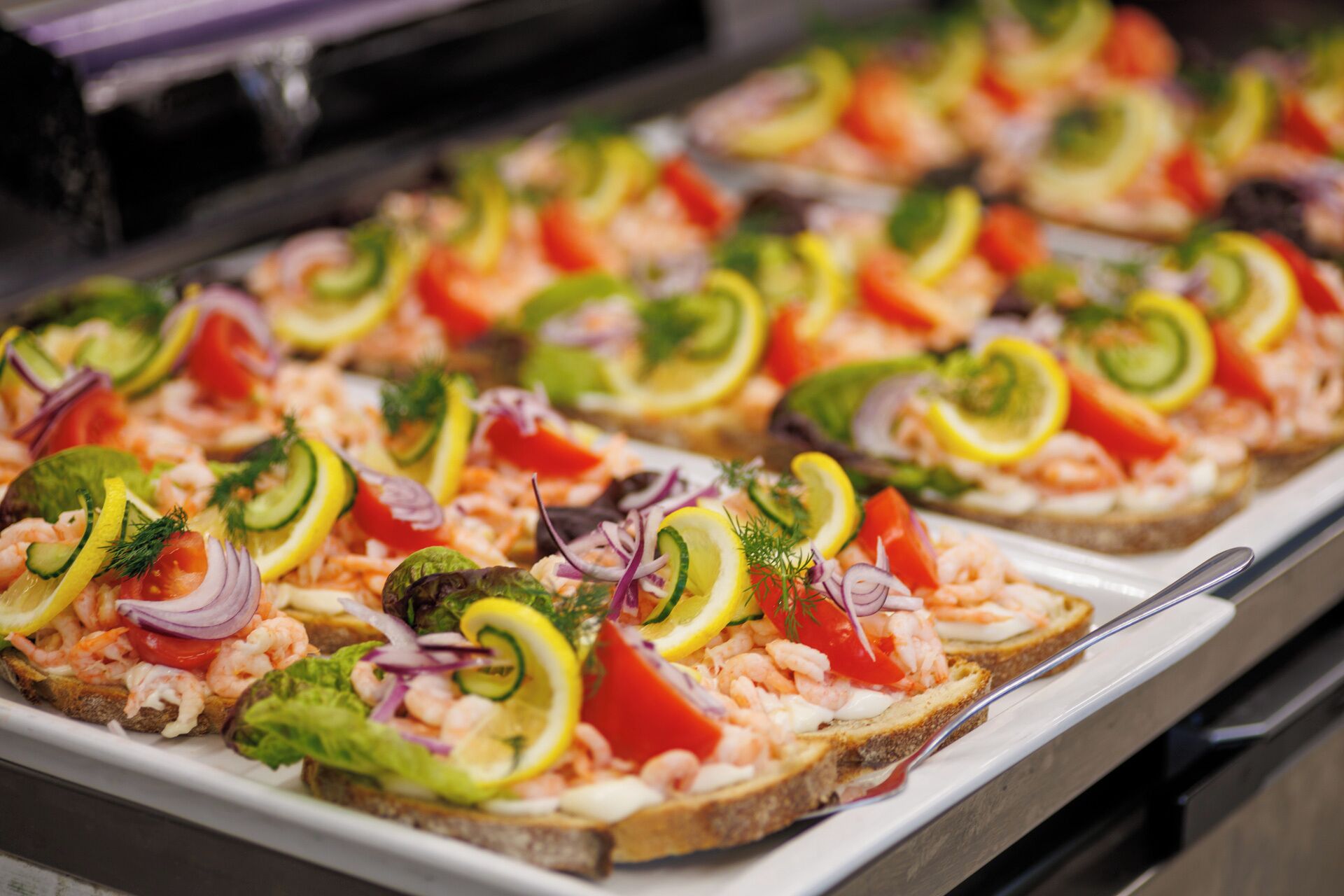 A buffet with shrimp-topped toast garnished with vegetables.