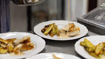 A kitchen scene with a person pouring sauce over food.