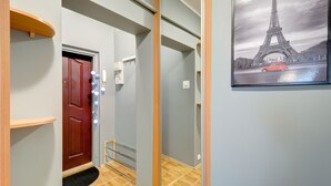 Um corredor com piso de madeira, uma porta vermelha e um quadro emoldurado da Torre Eiffel.
