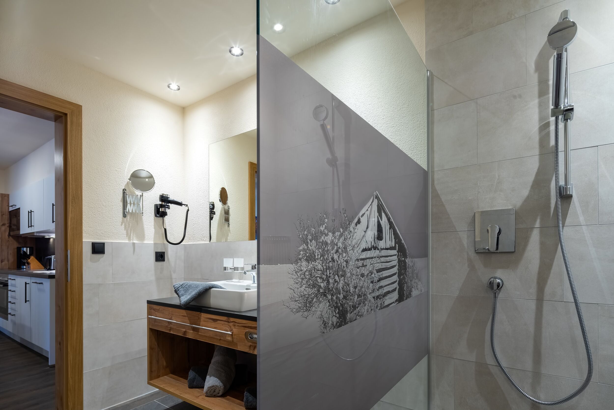 A modern bathroom with a shower, a sink, and a mirror.