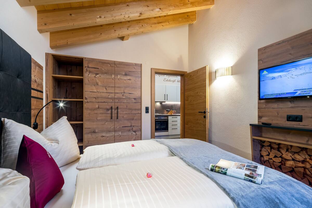 A bedroom with a bed, pillows, a TV, wooden cabinets, and a fireplace.