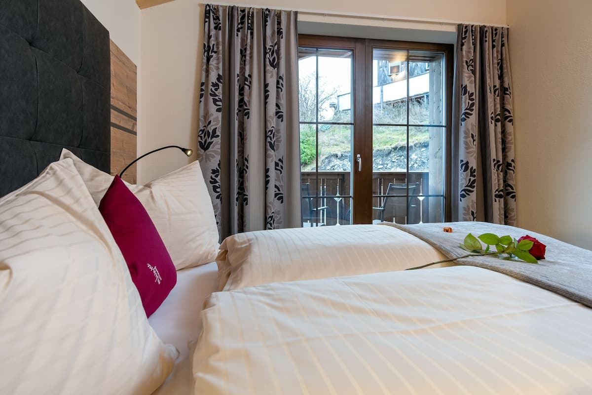 A hotel room with a large bed, a dark headboard, and a view of the outdoors through a sliding glass door.